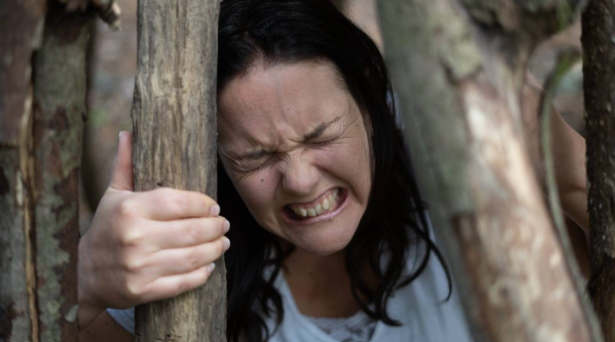 Evelyne Desrochers serrant des branches avec une expression intense.