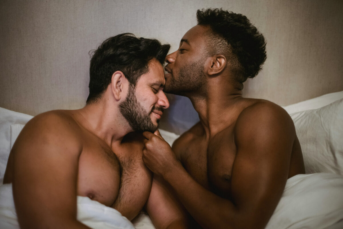 Couple d’hommes noirs et latinos partageant un moment de tendresse et de connexion intime au lit