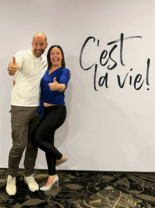 Evelyne Desrochers et François Lemay posant avec enthousiasme devant l’inscription « C’est la vie! ».